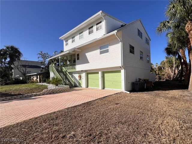 view of front of house with a garage, stairs, cooling unit, decorative driveway, and a porch