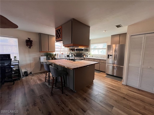 kitchen with stainless steel appliances, a wealth of natural light, butcher block countertops, and light hardwood / wood-style flooring