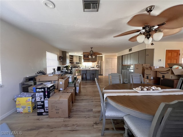 dining area with ceiling fan, sink, and light hardwood / wood-style flooring