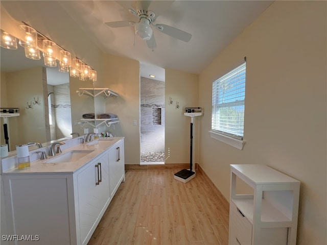 bathroom with hardwood / wood-style floors, vanity, ceiling fan, and a tile shower