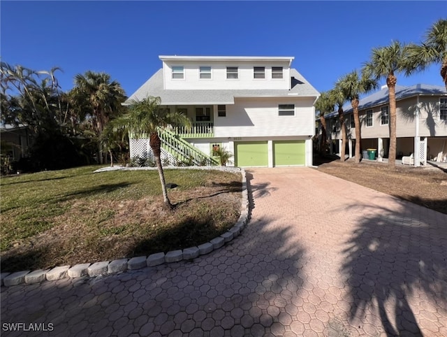 view of front of home featuring a front lawn, stairway, a porch, and decorative driveway