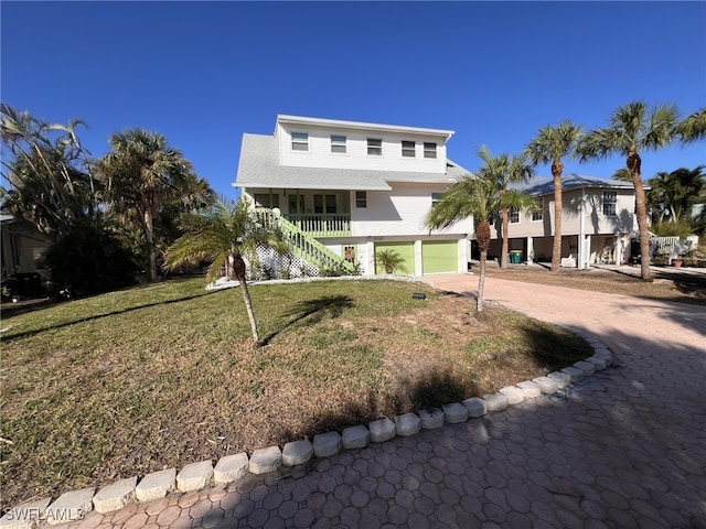 view of front of property featuring a front yard, covered porch, and a garage