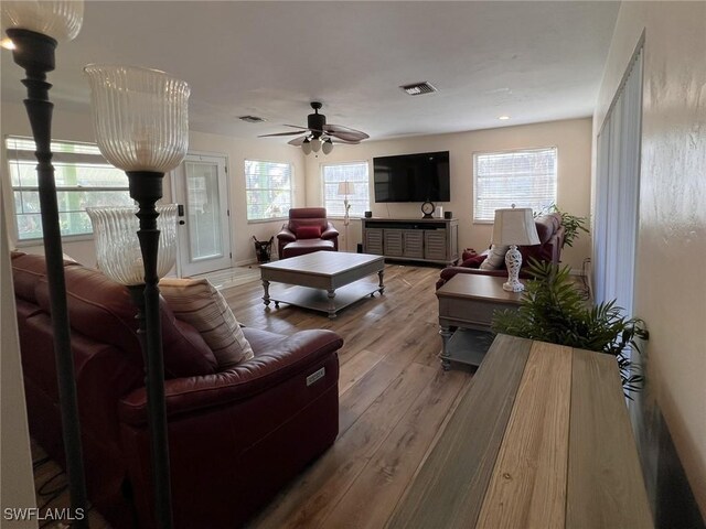 living room with ceiling fan, wood-type flooring, and a healthy amount of sunlight