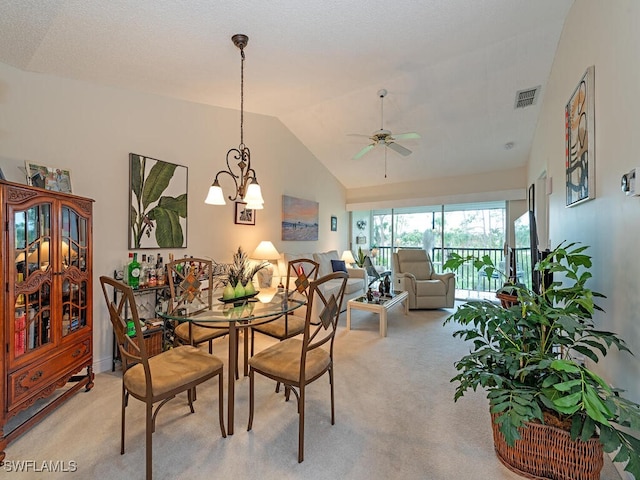 dining room with light carpet, ceiling fan with notable chandelier, and vaulted ceiling