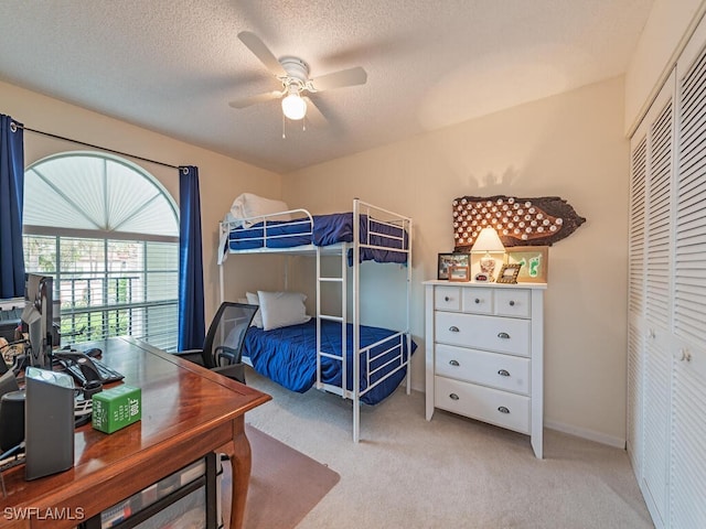 bedroom featuring a textured ceiling, ceiling fan, light carpet, and a closet