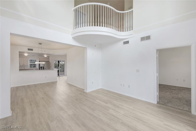 unfurnished living room with light hardwood / wood-style floors and a high ceiling