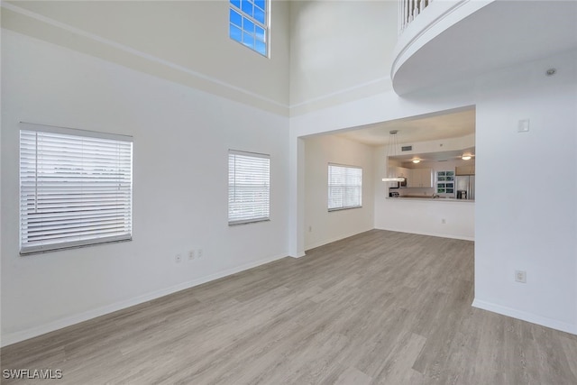 unfurnished living room with a high ceiling and wood-type flooring