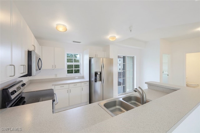 kitchen with white cabinetry, kitchen peninsula, sink, and stainless steel appliances