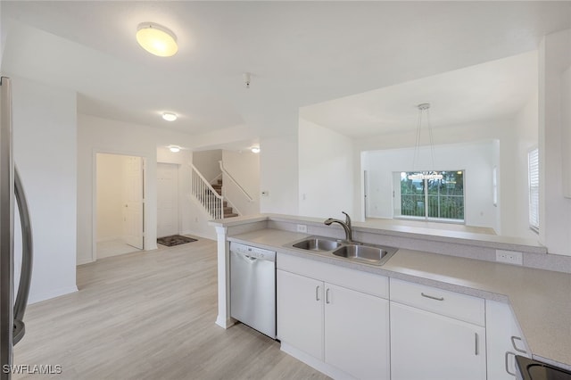 kitchen featuring light wood-type flooring, appliances with stainless steel finishes, hanging light fixtures, sink, and white cabinets