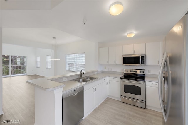 kitchen with light wood-type flooring, appliances with stainless steel finishes, decorative light fixtures, sink, and kitchen peninsula