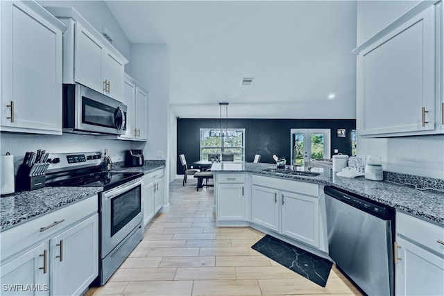 kitchen with stainless steel appliances, kitchen peninsula, sink, light stone countertops, and white cabinetry