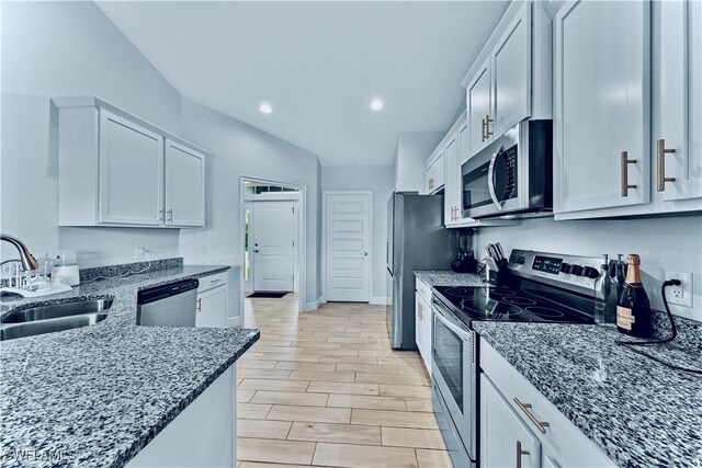 3002 40th St W, Lehigh Acres, FL 33971 - kitchen with appliances with stainless steel finishes, a sink, dark stone counters, recessed lighting, and light wood-type flooring