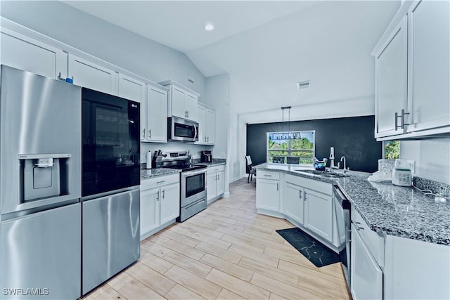 3002 40th St W, Lehigh Acres, FL 33971 - kitchen featuring stainless steel appliances, a sink, white cabinets, a peninsula, and vaulted ceiling