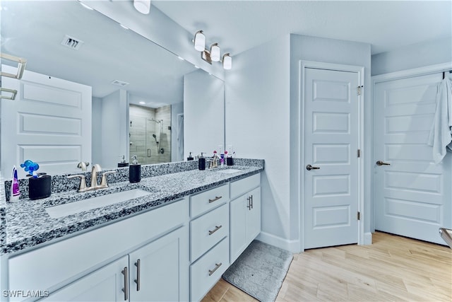 bathroom featuring hardwood / wood-style floors, vanity, and a shower with door