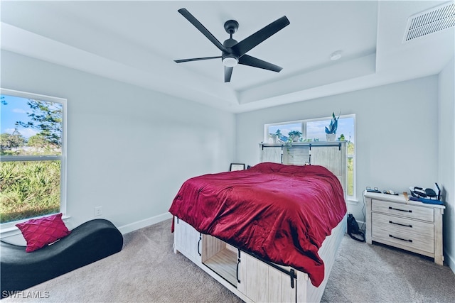 carpeted bedroom featuring ceiling fan and a raised ceiling