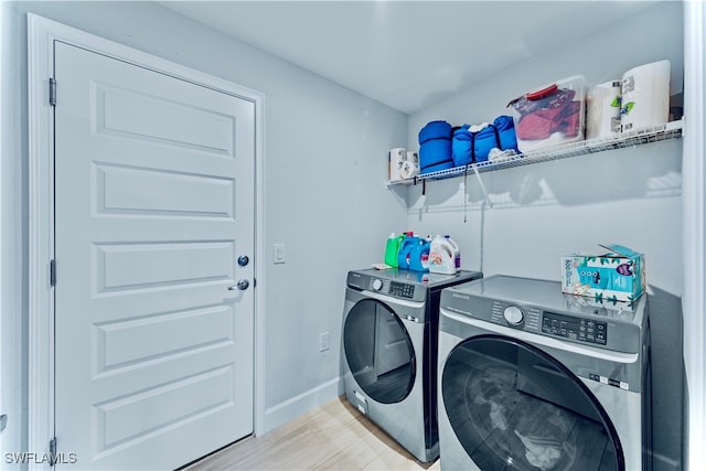 laundry area with light wood-type flooring and washing machine and clothes dryer