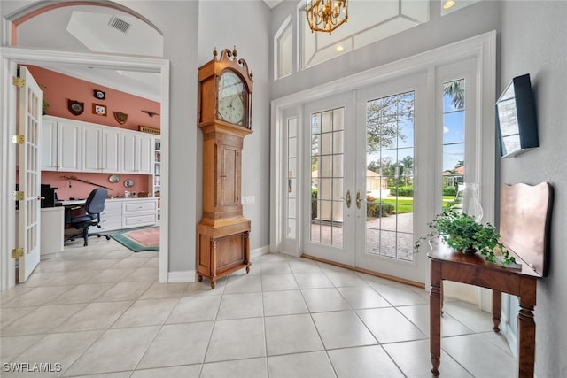 entryway with built in desk, a high ceiling, light tile patterned floors, and french doors