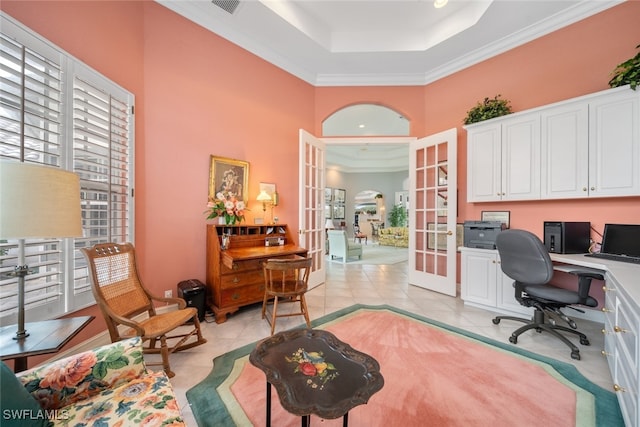 tiled office space featuring french doors, built in desk, ornamental molding, a towering ceiling, and a raised ceiling