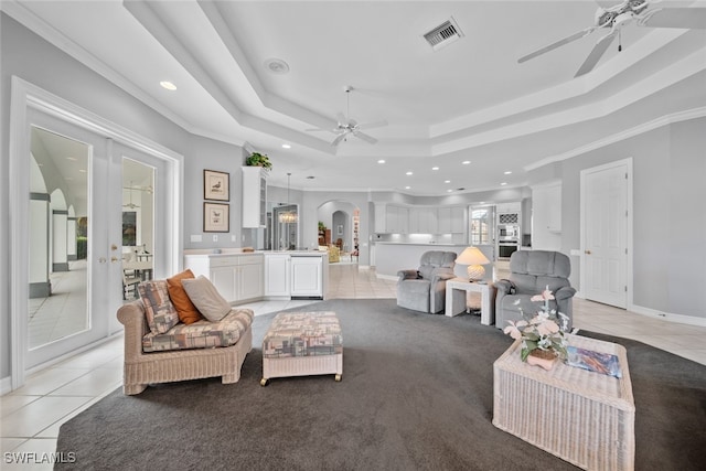 tiled living room featuring a tray ceiling, ceiling fan, and crown molding