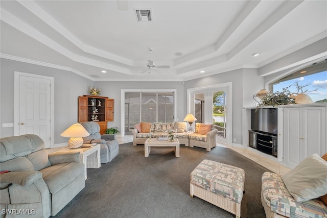 living room featuring ceiling fan, a raised ceiling, crown molding, and light colored carpet