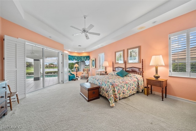 carpeted bedroom featuring access to outside, a tray ceiling, and ceiling fan