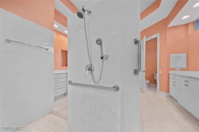 bathroom featuring toilet, vanity, tile patterned flooring, and tiled shower