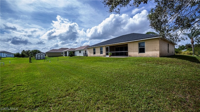 rear view of house featuring a lawn and a storage shed