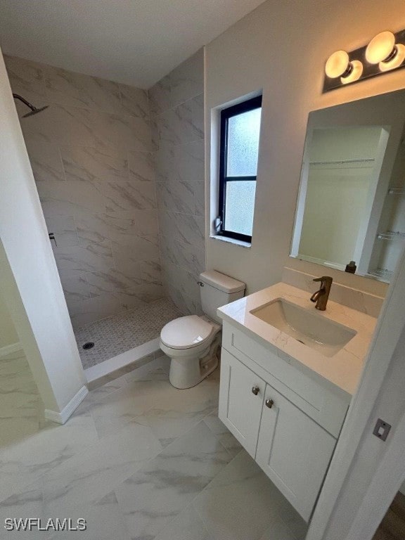 bathroom with tiled shower, vanity, and toilet