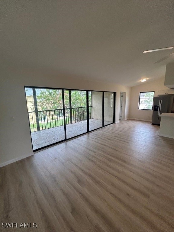 unfurnished living room featuring light wood-type flooring, lofted ceiling, and ceiling fan