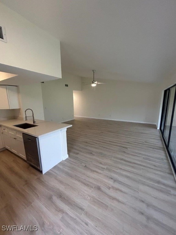 kitchen with a sink, open floor plan, white cabinetry, a ceiling fan, and light countertops
