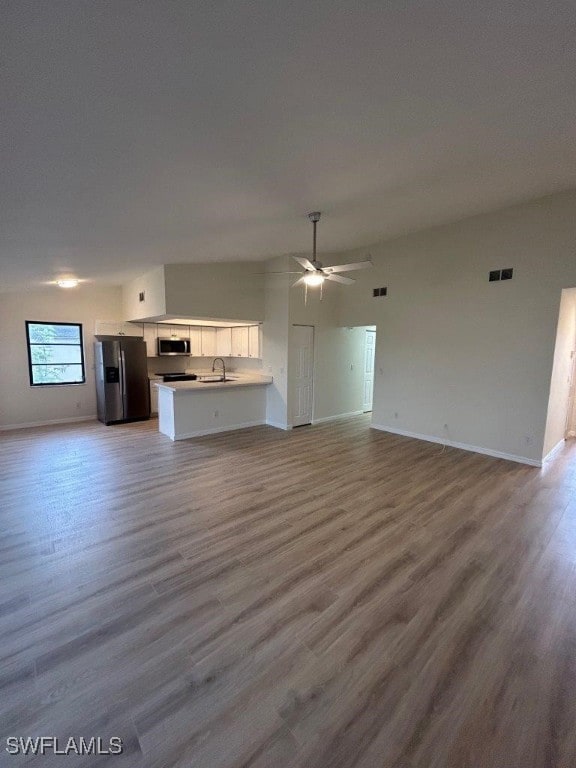 unfurnished living room featuring light hardwood / wood-style floors, ceiling fan, and sink