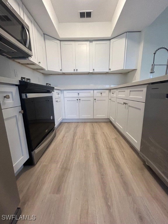 kitchen featuring white cabinetry, appliances with stainless steel finishes, sink, and light hardwood / wood-style flooring