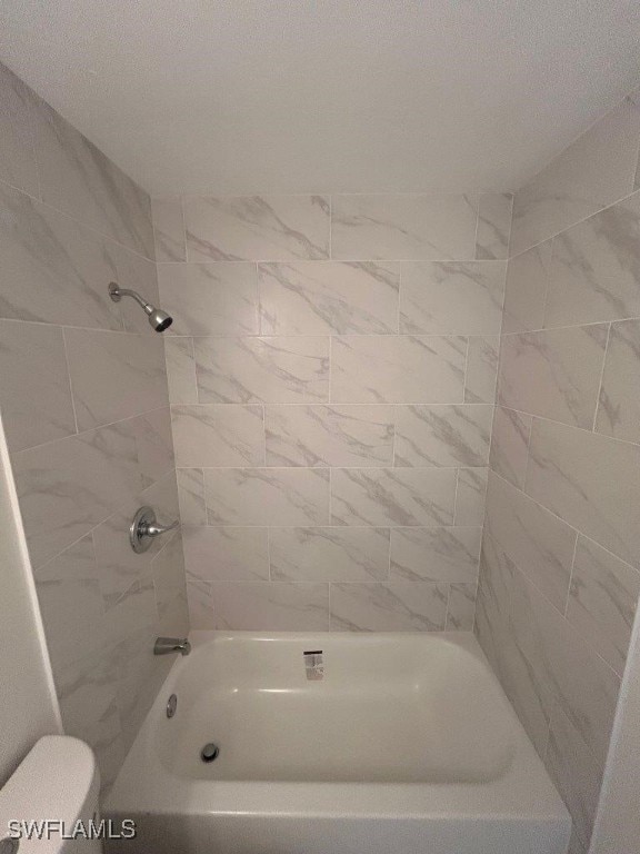 bathroom featuring toilet and tiled shower / bath combo