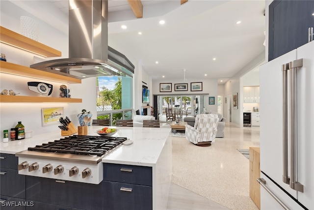 kitchen with island exhaust hood, high end white fridge, light stone countertops, and stainless steel gas cooktop