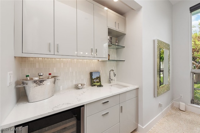 bar with wine cooler, light stone countertops, sink, and decorative backsplash