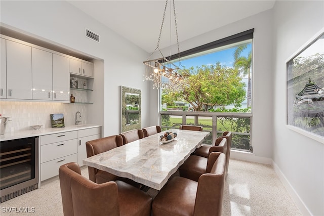 dining area with a wealth of natural light, beverage cooler, lofted ceiling, and indoor wet bar