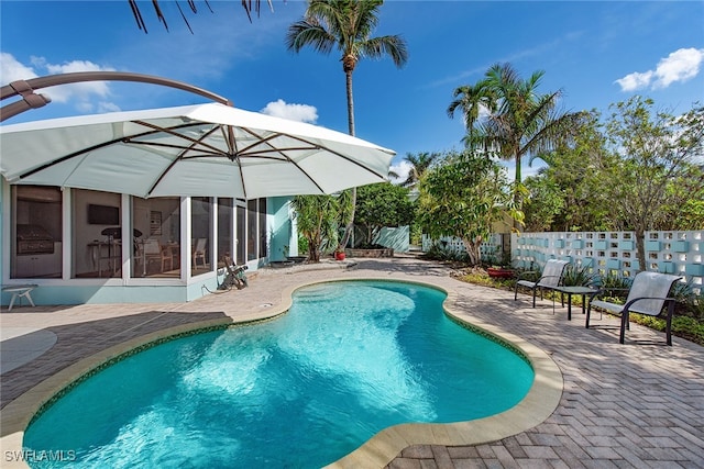 view of swimming pool with a sunroom and a patio