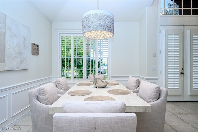 dining room with a notable chandelier, light tile patterned floors, and vaulted ceiling