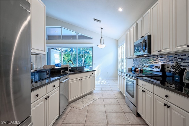 kitchen featuring tasteful backsplash, appliances with stainless steel finishes, sink, vaulted ceiling, and white cabinets