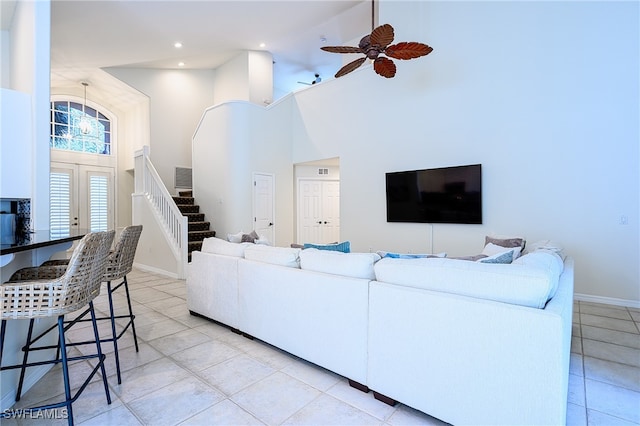 living room with a towering ceiling, ceiling fan, and light tile patterned floors