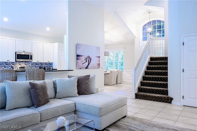 tiled living room with a high ceiling and a chandelier