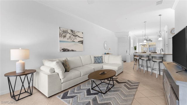 living room featuring light tile patterned flooring, an inviting chandelier, and ornamental molding