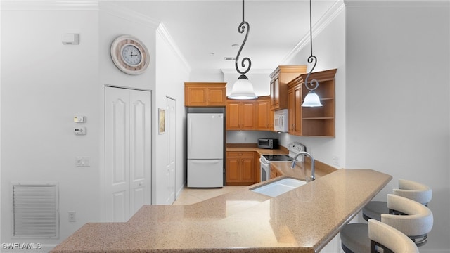 kitchen featuring kitchen peninsula, a breakfast bar area, hanging light fixtures, white appliances, and crown molding