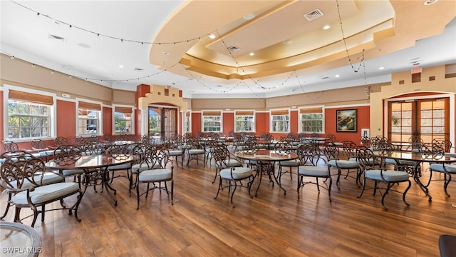 dining area featuring hardwood / wood-style flooring, plenty of natural light, and a raised ceiling