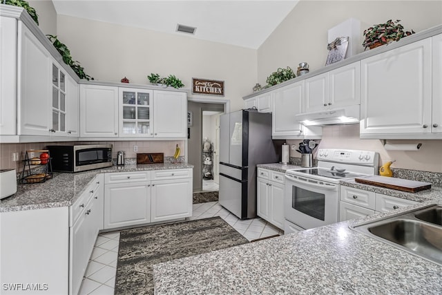 kitchen featuring tasteful backsplash, stainless steel appliances, light tile patterned floors, white cabinets, and lofted ceiling