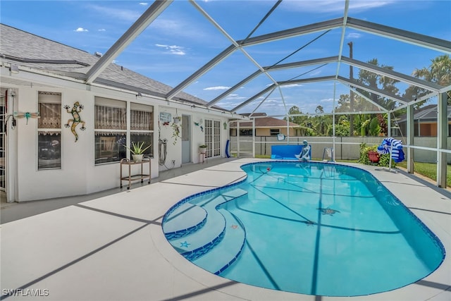 view of swimming pool with glass enclosure and a patio