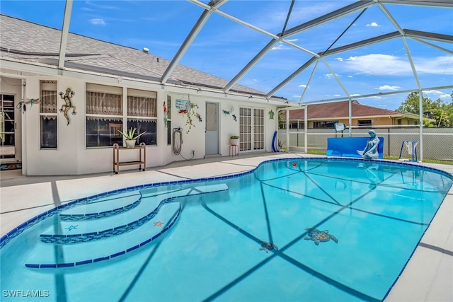 view of pool with glass enclosure and a patio area