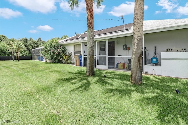 back of house with a lanai and a lawn