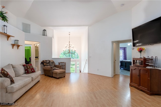 living room with high vaulted ceiling, light hardwood / wood-style floors, and an inviting chandelier