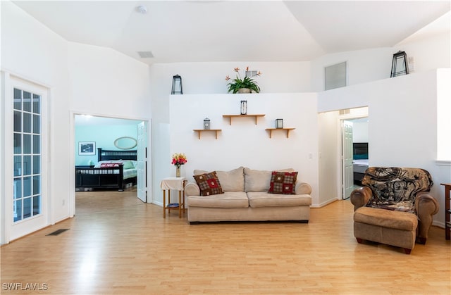 living room with high vaulted ceiling and light hardwood / wood-style flooring